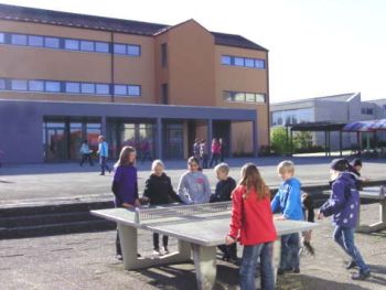 Freibühlschule Großengstingen. Kinder spielen an einer Tischtennisplatte im Schulhof.