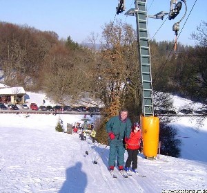 Zwei Personen werden auf Skiern mit dem Skilift Engstingen den Hang hinaufgezogen. Im Hintergrergrund der Parkplatz mit Autos